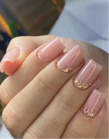 Unhas alongadas em tom nude com detalhe em glitter